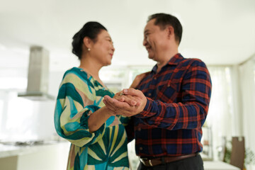 Happy aged Vietnamese couple enjoying romantic dance at home