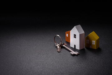 A small wooden house and keys as an idea for investing in your own home and achieving the goal of buying real estate
