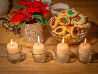 Christmas. Advent. Antique-style still life with candles, cake and poinsettia christmas star plant. - 699236307