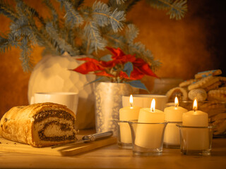 Christmas. Advent. Antique-style still life with candles, cake and poinsettia christmas star plant. - 699236561