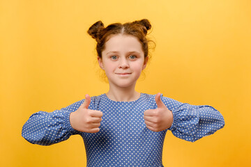 Portrait of pretty smiling little girl kid gesturing thumbs up, happy looking at camera, posing...