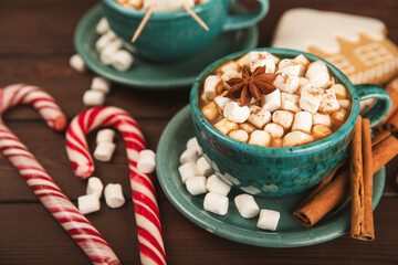 Hot drink with marshmallows and candy cane in  cup on a texture table.Cozy seasonal holidays.Hot cocoa with gingerbread Christmas cookies.Hot chocolate with marshmallow and spices.Copy space.