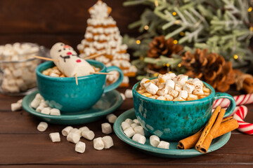 Hot drink with marshmallows and candy cane in  cup on a texture table.Cozy seasonal holidays.Hot cocoa with gingerbread Christmas cookies.Hot chocolate with marshmallow and spices.Copy space.