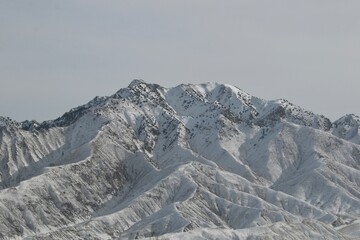 a snowy mountain with no trees, and a large snow covered mountain