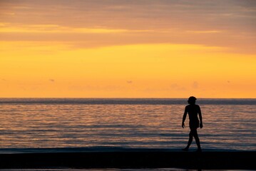 Fototapeta na wymiar Against the background of a bright sunset yellow man walking