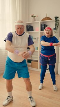 Funny senior couple in sportswear dancing on cellphone camera, filming a video