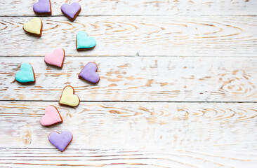 Pink, violet, yellow and green heart cookies on a white wooden background