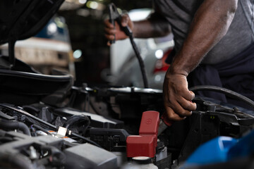 close up mechanic worker hands holding battery cable for jumping battery of a car in automobile...