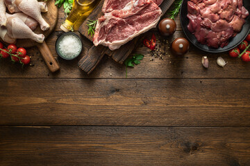 Set of raw ingredients for preparing food, liver, chicken legs and two beef steaks on a wooden...