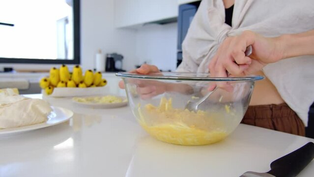 woman in kitchen make homework. woman stirs omelette with cheese on bowl at table. Domestic kitchen interior. Breakfast preparation.
