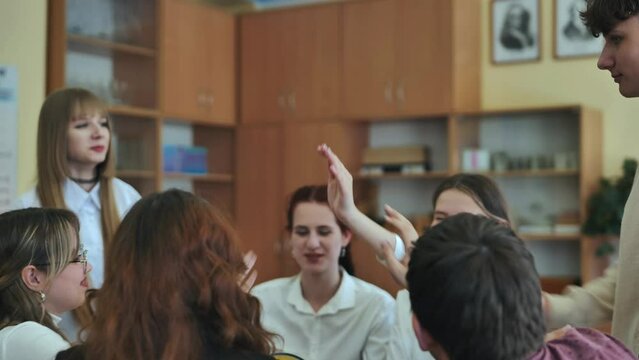 High school seniors join hands in class as a sign of working together.