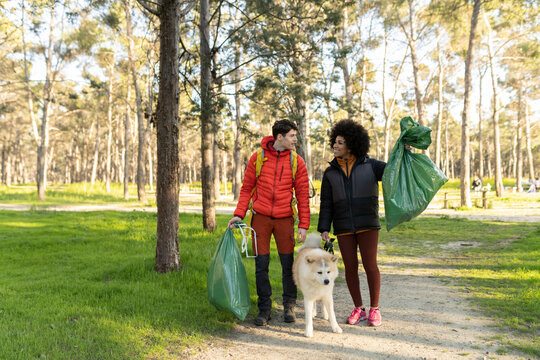 young environmentalists collect garbage from the forest with their dog - volunteers -