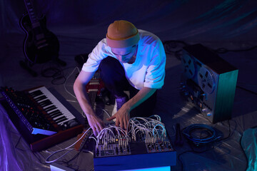 High angle shot of male musician sitting on floor of studio while experimenting with recorded audio...