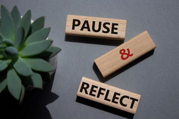 Pause and Reflect symbol. Concept words Pause and Reflect on wooden blocks. Beautiful grey...