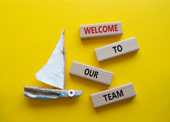 Welcome to our team symbol. Concept words Welcome to our team on wooden blocks. Beautiful yellow background with boat. Business and Welcome to our team concept. Copy space.