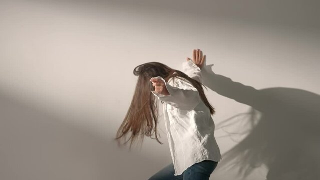 Portrait of attractive female model in negative mood. Studio shot of brunette woman in hysterical mood, screaming crying and hitting the wall.