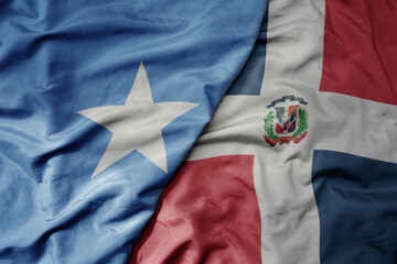 big waving national colorful flag of dominican republic and national flag of somalia .