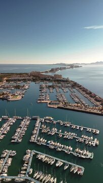 Port and Mediterranean coastline from a drone's eye view in vertical format. Tomas Maestre harbor in La manga, Murcia, Spain. Division of the Mar Menor and Mediterranean Sea.