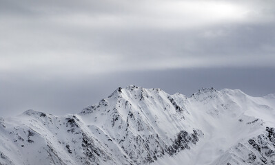 Fototapeta na wymiar High snowy mountains and gray sky before blizzard