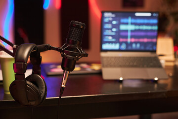 Close up shot of professional condenser microphone and headphones hanging on flexible mic stand in studio - obrazy, fototapety, plakaty
