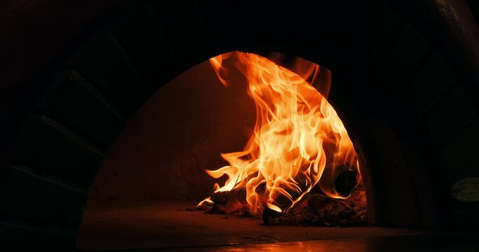 Firewood burning in a stone oven in a restaurant's bakery to bake pizza, pide or bread. Burning fire in stone oven. Close-up, slow motion