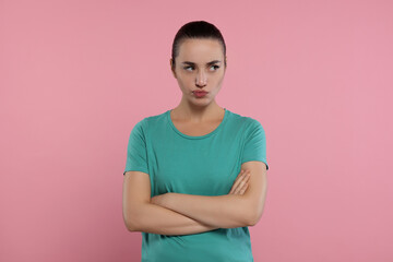 Fototapeta premium Portrait of resentful woman with crossed arms on pink background