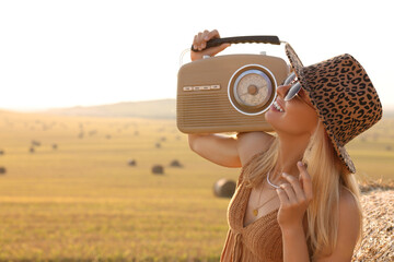 Happy hippie woman with radio receiver in field, space for text