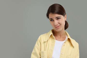 Portrait of resentful woman on grey background, space for text