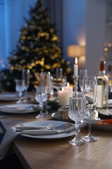 Christmas table setting with festive decor and dishware in room. Space for text