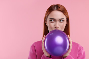 Woman inflating purple balloon on pink background, space for text