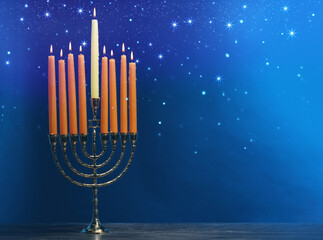 Hanukkah celebration. Menorah with burning candles on wooden table against blue background, space for text
