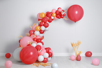 Balloon garland near white wall in room. Festive decor