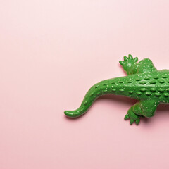 Tail of green crocodile toy on pastel pink background. Minimal art concept.