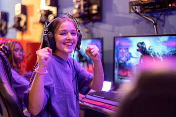 Portrait of young gamer girl playing online video games celebrating that she is winning the game
