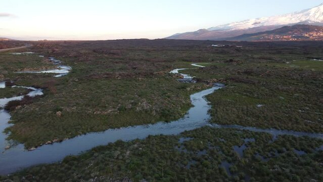 A seasonal river flows under the massive snowcovered Etna volcano. Favare Santa Venera