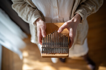 Girl hands holding kalimba closeup, traditional acoustic African wooden instrument with metal keys...