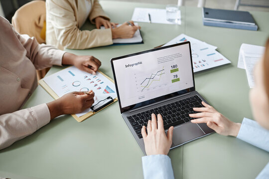 Over The Shoulder Shot Of Unrecognizable Woman Using Laptop With Business Report Infographic On Screen During Business Meeting In Office