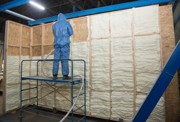Insulation of walls with foam, energy and heat saving of walls, worker treats walls with foam - obrazy, fototapety, plakaty