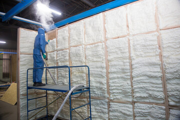 Insulation of walls with foam, energy and heat saving of walls, worker treats walls with foam - obrazy, fototapety, plakaty