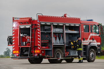 A firefighter meticulously prepares a modern firetruck for a mission to evacuate and respond to...