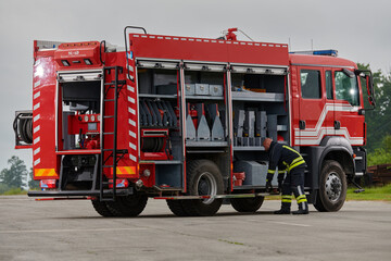 A firefighter meticulously prepares a modern firetruck for a mission to evacuate and respond to...