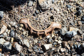 Old broken rusty piece of machinery on the ground among rocks