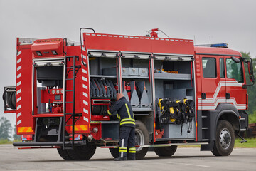 A firefighter meticulously prepares a modern firetruck for a mission to evacuate and respond to...
