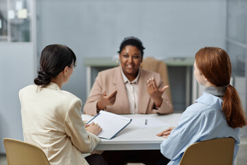 Back view of two unrecognizable woman HR representatives sitting at table in company office while...