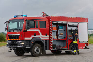 A firefighter meticulously prepares a modern firetruck for a mission to evacuate and respond to...