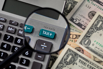Tax calculator, magnifying glass and cash money. Income, sales and property taxes concept.