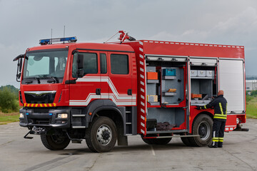 A firefighter meticulously prepares a modern firetruck for a mission to evacuate and respond to...