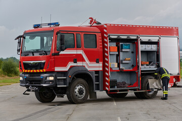 A firefighter meticulously prepares a modern firetruck for a mission to evacuate and respond to...