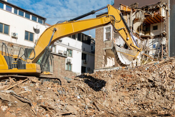 Obraz premium Freeing up space for construction of new building.Process of demolition of old building dismantling. Excavator breaking old house. Destruction of dilapidated housing for new development