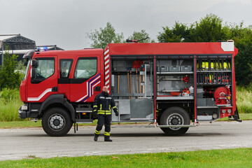 A firefighter meticulously prepares a modern firetruck for a mission to evacuate and respond to...
